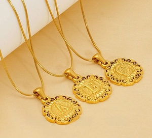 Vue macro de pendentifs lettres A, B, C en acier doré avec chaîne en maille serpent