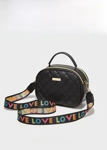 Detail der gesteppten schwarzen Umhängetasche mit Goldlogo und buntem LOVE-Gurt