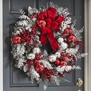 Frosted Christmas wreath with red bow and silver ornaments on a dark grey door
