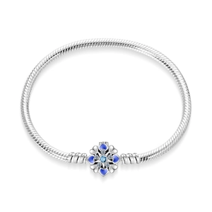 Macro shot of silver snake chain bracelet with blue snowflake charm and crystal inlay
