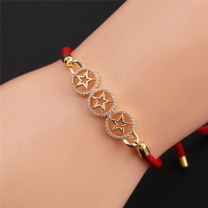 Detail of red braided star bracelet with gold plating and sparkling cubic zirconia stones