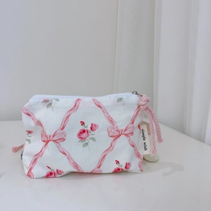 Macro detail of pink floral cotton pouch with ribbon pattern and zipper puller