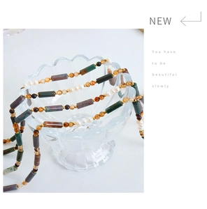 Detail of handmade beaded necklace with natural stones and freshwater pearls on glass