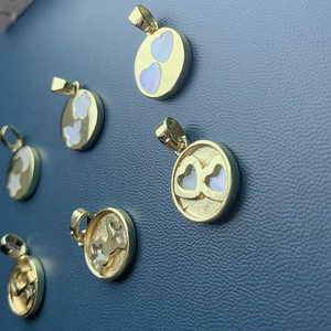 Detailed view of golden pendants with mother-of-pearl in heart and cloud designs