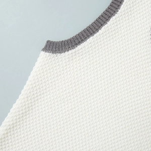 Detail of white knit fabric with textured pattern and grey ribbed neckline stitching
