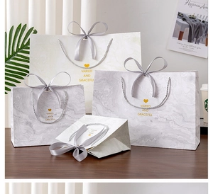 Detail of marble pattern gift bags with grey silk ribbons and golden elegant lettering