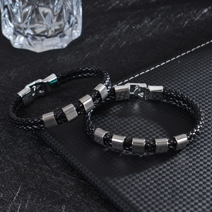 Detailed close-up of men's braided black leather bracelet with engraved silver metal beads