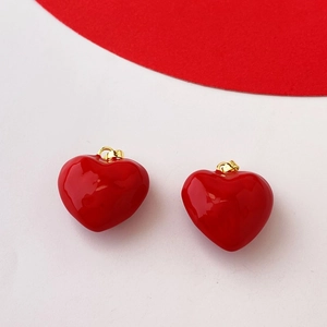 Detail view of glossy red heart pendants with gold metal clasps on white background