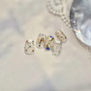 Detail von böhmischen Goldfolien-Nagelstickern mit blauen Steinen und Reliefmustern