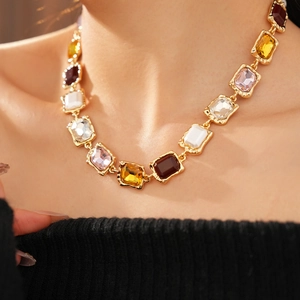 Macro shot of vintage gold chain necklace featuring multi-colored rectangular gemstones