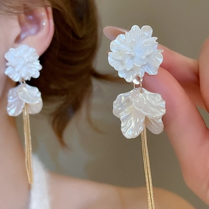 Close-up of elegant acrylic flower petal tassel earrings on model with golden chains