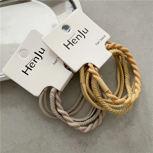Detail of beige and yellow braided hair bands on cardboard display card