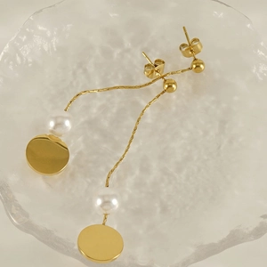 Detail view of 18K gold tassel earrings with pearls on a textured glass tray