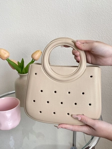 Détail du sac de plage beige en EVA avec design ajouré porté par une personne