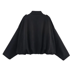 Detail of a black oversized bomber jacket showing shoulder epaulets and elastic hemline