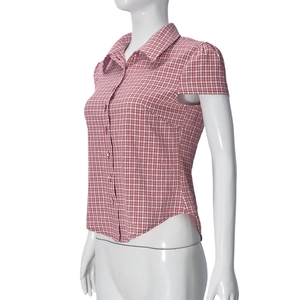 Detail of red and white checkered short sleeve shirt with covered buttons on a mannequin