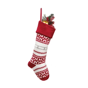Knitted red and white Christmas stocking with snowflake patterns and festive pine fillings
