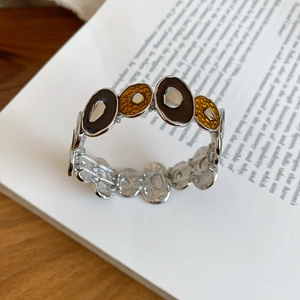 Detail of vintage silver bracelet with brown enamel on an open book over a wooden desk