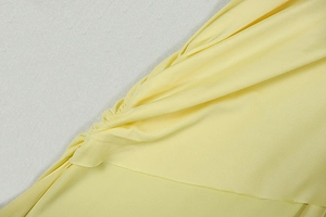 Close-up of yellow sleeveless mini dress showing ruched side seam and knit texture