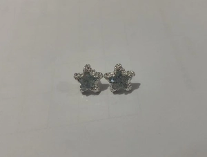 Macro view of silver star stud earrings with central light blue crystal inlay