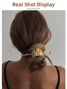Detail of wavy gold hair clip and pearl tassel hair pin set on a model's hair bun