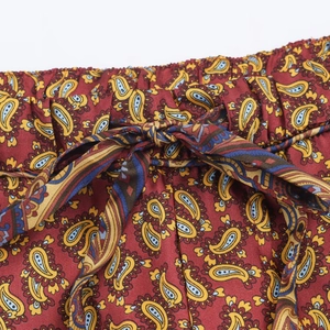 Detail of red paisley print pants featuring a drawstring elastic waist and twill texture