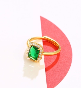 Detail of adjustable gold ring with large emerald cut green stone and white crystal halo