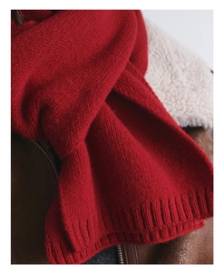 Detail of dark red wool knitted scarf with ribbed edge and textured weave detail