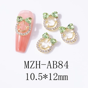 Detail of smile face nail charms with green heart crystals and inlaid rhinestones