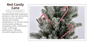Detail of handmade red and white candy cane ornaments hanging on a snowy Christmas tree