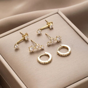 Three-piece gold copper earring set with white zircon stones on champagne silk