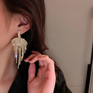 Close-up of elegant leaf tassel earrings with rhinestones on a female model
