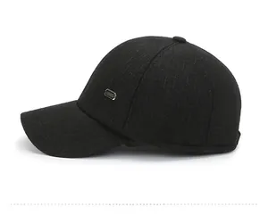 Detail of the black baseball cap showing the side metal logo and woven fabric texture