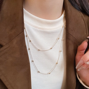 Close-up of double layered gold bead necklace styled on a model for a layered look