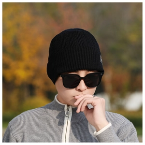 Close-up of black ribbed knit beanie with side patch on male model in autumn setting