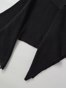 Detailed close-up showing the fine ribbed texture and asymmetric hem of the wool cape