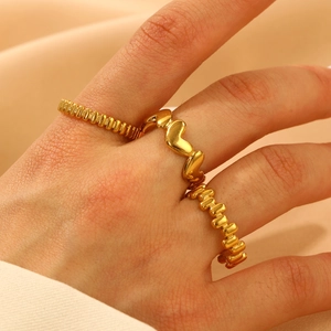 Détail de trois bagues en titane plaqué or 18 carats avec motifs de cœur et perles