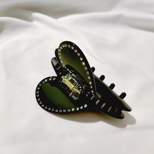 Dettaglio molletta per capelli nera a forma di cuore con strass su seta bianca elegante