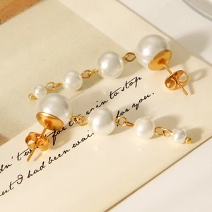 Detail of French style gold tassel earrings with gradient white pearls on vintage paper