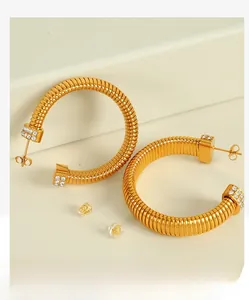 Macro shot of gold spiral twist hoop earrings with sparkling rhinestones and metal backings