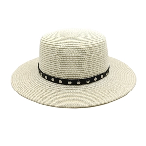 Détail d'un chapeau canotier en paille avec ruban noir et clous métalliques argentés
