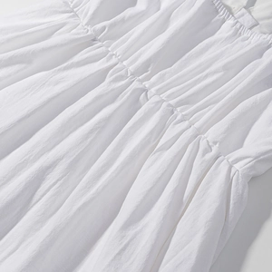 Detail of white cotton fabric showing intricate smocked waist and textured embroidery
