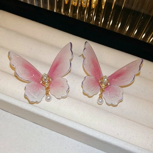 Gros plan sur des boucles d'oreilles papillon dégradé rose avec cristaux et perles