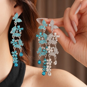 Close-up of dangling butterfly tassel earrings with sparkling blue and white crystals