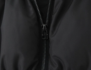 Detail of the high-quality metal zipper on a black winter jacket with smooth synthetic fabric
