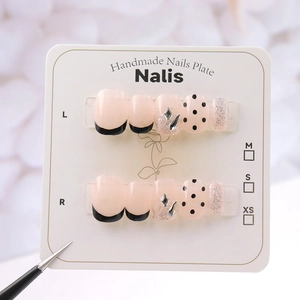 Detail of handmade press-on nails with black french tips and silver glitter accents