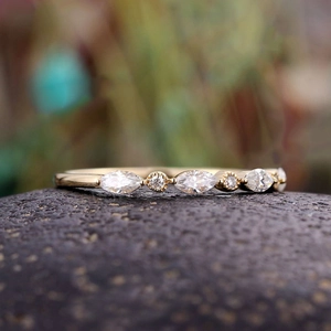 Eleganter Goldring mit abwechselnden Marquise- und Rundschliff-Kristallen auf Stein