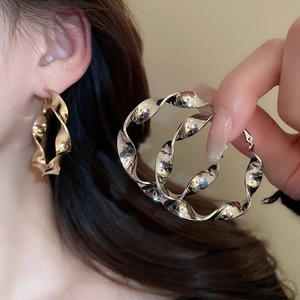 Vue détaillée des boucles d'oreilles créoles torsadées en métal doré et argenté poli