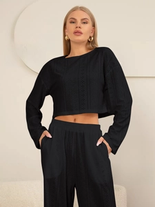 Gros plan sur la texture dentelle noire ajourée de l'ensemble haut manches longues et pantalon