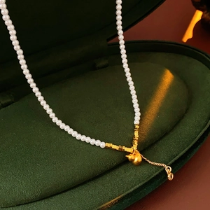 Close-up of elegant pearl and gold necklace with gourd pendant in a gift box